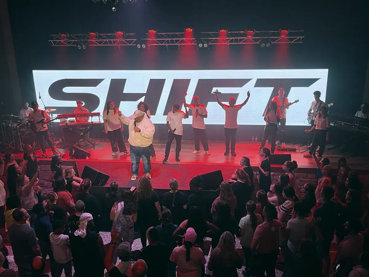 Audience facing a full-stage LED wall in a packed auditorium